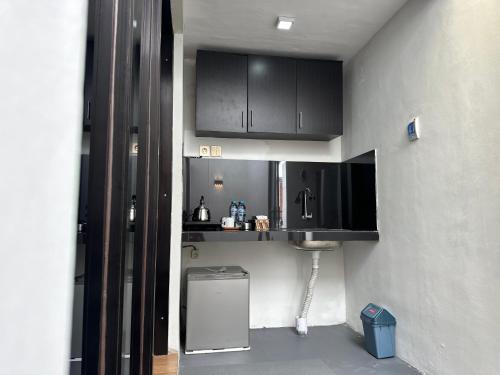 a small kitchen with black cabinets and a sink at alopa villas in Beran-kidul