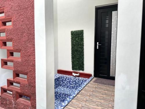 a door with a green hedge next to a wall at alopa villas in Beran-kidul