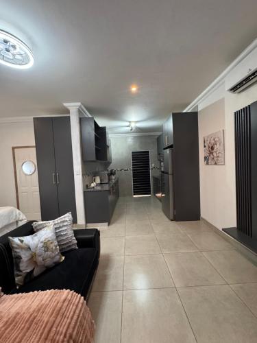 een woonkamer met een bank en een keuken bij WeMvula Guesthouse in Mtubatuba