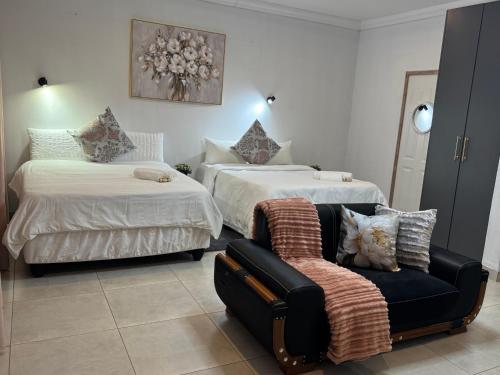 a hotel room with two beds and a chair at WeMvula Guesthouse in Mtubatuba