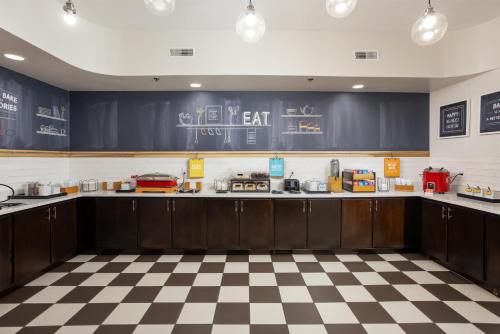 Una cocina con gabinetes de madera oscura y piso a cuadros. en Hampton Inn Carrollton KY, en Carrollton