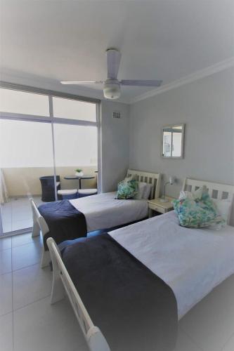 a bedroom with two beds and a ceiling fan at Sea Lodge 61 in Durban