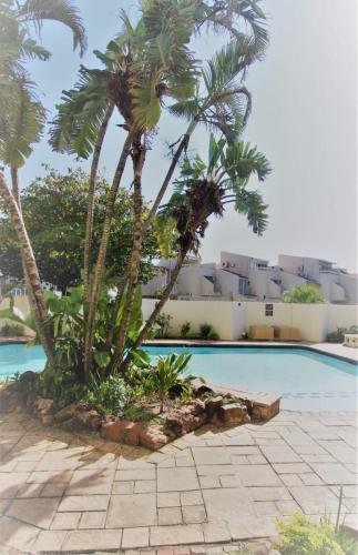 a swimming pool with palm trees in front of a building at Sea Lodge 61 in Durban