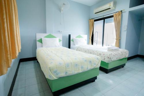 Un dormitorio con dos camas y una ventana. en Thongkon Hotel, en Surin
