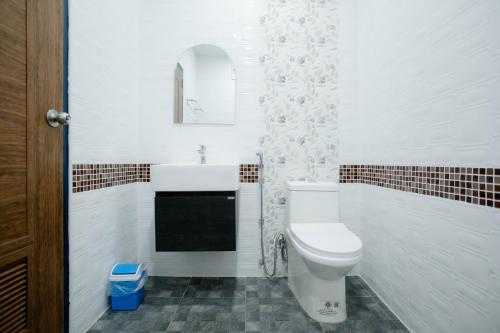 Un baño con un inodoro blanco y un lavabo. en Thongkon Hotel, en Surin