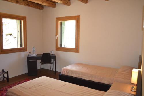 a bedroom with two beds and a desk and two windows at Casale La Rocchetta in Lonigo
