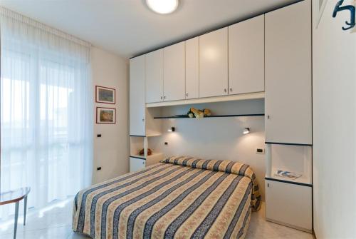 une chambre avec un lit avec une couverture rayée dans l'établissement Auriga del Sole, à Bibione