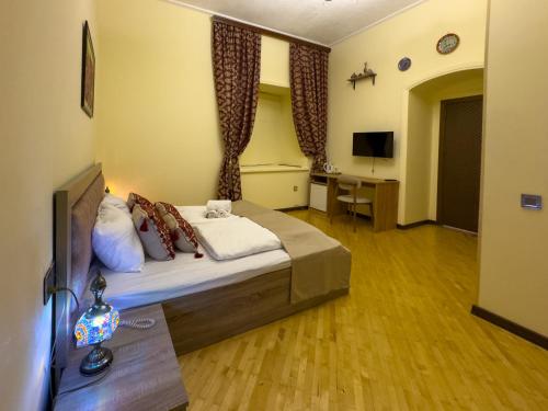 a bedroom with a bed and a desk and a television at Suvenir Hotel in Baku