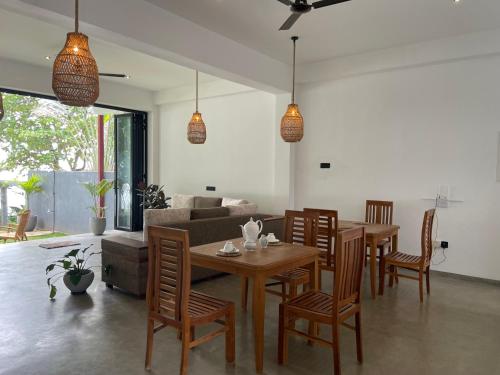 a living room with a wooden table and chairs at Bloom Beach Villa in Batigama