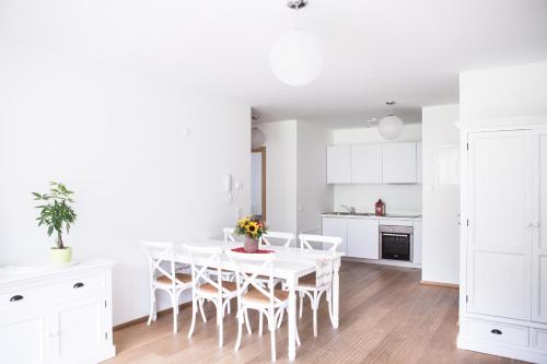 a white kitchen with a white dining room table and chairs at Residence Mariagrazia - Kärnten Card im Sommer inklusive in Bad Kleinkirchheim