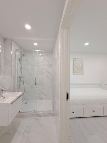 a white bathroom with a shower and a sink at St Faiths - City Centre Apartment in Norwich