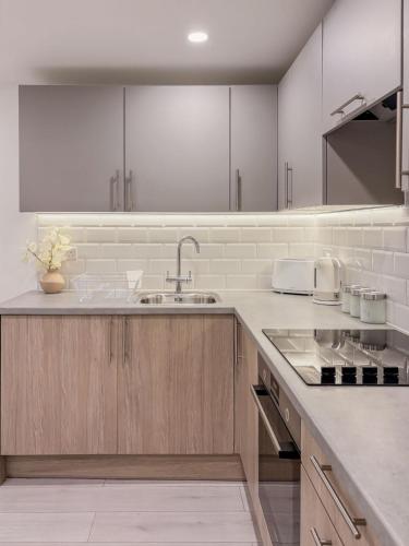 a kitchen with white cabinets and a sink at St Faiths - City Centre Apartment in Norwich