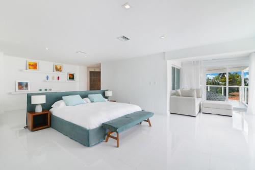 een witte slaapkamer met een bed en een bank bij Villa Moonlight Haven in Miami Beach