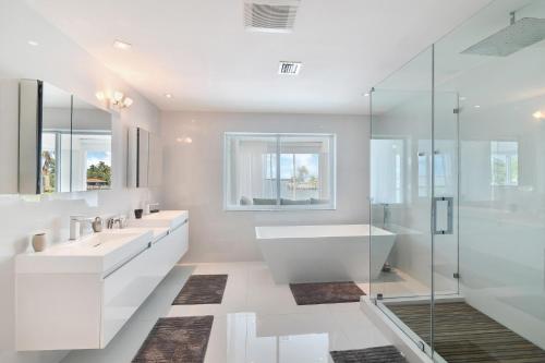 een badkamer met twee wastafels, een bad en een douche bij Villa Moonlight Haven in Miami Beach