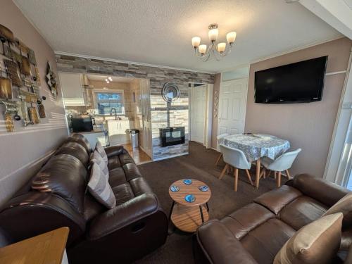 a living room with a leather couch and a table at 179, Two bed chalet on Sund0wner Holiday Park - Sleeps 4, free WiFi, sorry no pets - entertainment options close by in Hemsby