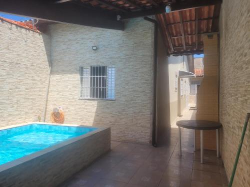 モンガグァーにあるEPK House Mongaguáのテーブルとスツールが置かれた建物内の大きなプール