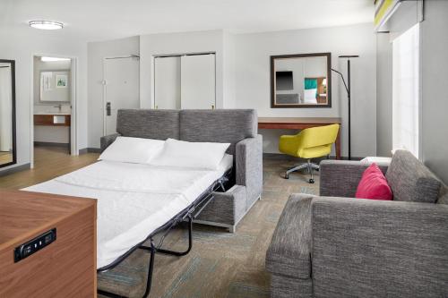 a bedroom with a bed and a yellow chair at Hampton Inn Kansas City The Legends in Kansas City