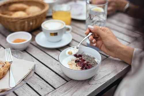 a person eating a bowl of food on a wooden table at Hilburger Hotel in Schenna