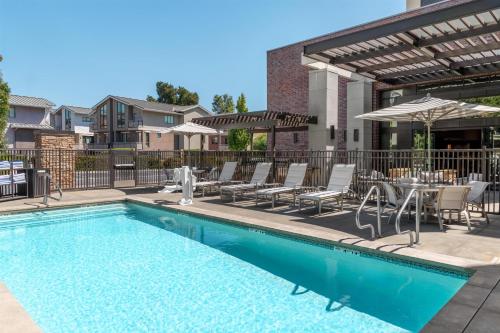 a swimming pool with chairs and a table at Homewood Suites by Hilton Palo Alto in Palo Alto