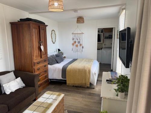 a bedroom with a bed and a couch and a tv at Sunrise on the Tamar in Deviot