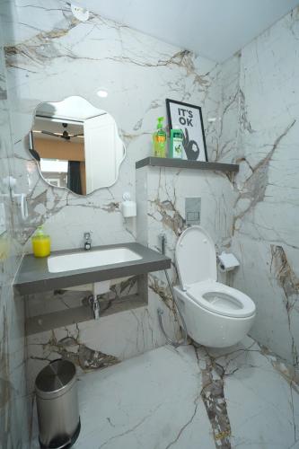 a marble bathroom with a toilet and a sink at UHomes Pune airport in Pune