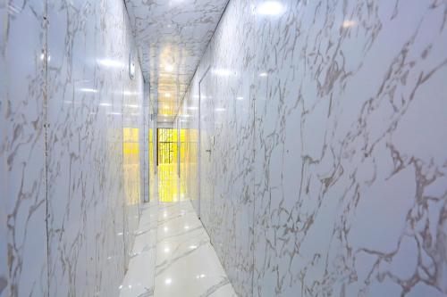 un pasillo con una pared de mármol y una puerta amarilla en Hotel O Happy Hours, en Nueva Delhi