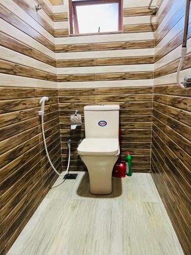 a bathroom with a toilet in a room with wooden walls at Florance Nice Hotel Weligama in Weligama