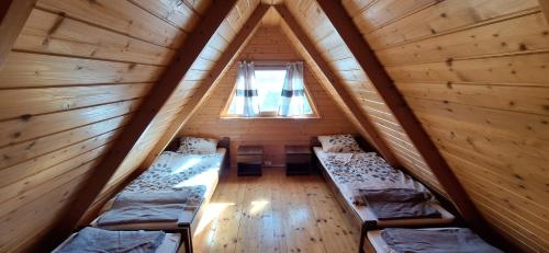 a attic room with three beds and a window at Uroczysko Domki in Zarzecze
