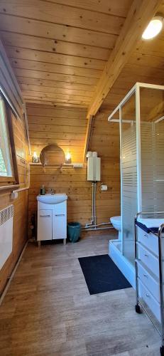 a bathroom with a wooden ceiling with a sink at Uroczysko Domki in Zarzecze