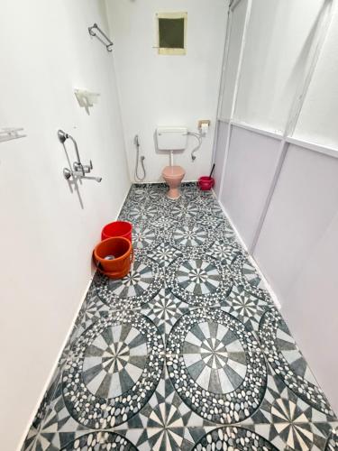 a bathroom with a toilet and a tile floor at SHIV SAI HUTS in Canacona