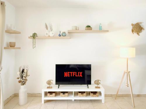 a living room with a tv on a white table at 5-Min Walk to Beach - Bright 2-BR Home with Private Garden & Sunset Views in Voroklini