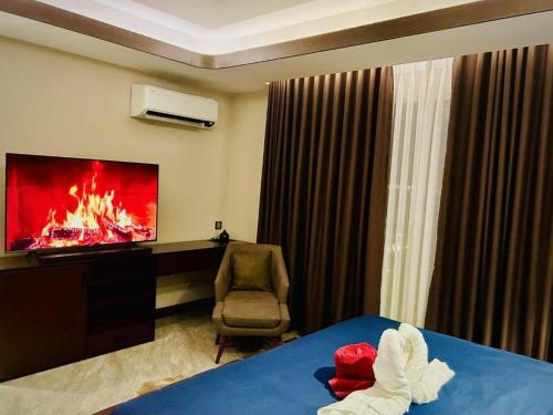 a hotel room with a tv and a bed and a chair at One Euphoria Prime Suite Hotel Angeles city in Malabañas