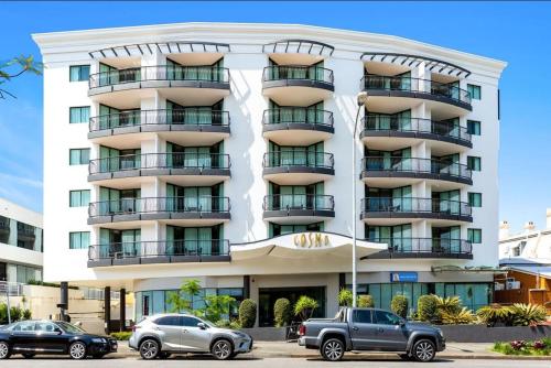 a large white building with cars parked in front of it at Cosmo Apartment Hotel in Brisbane