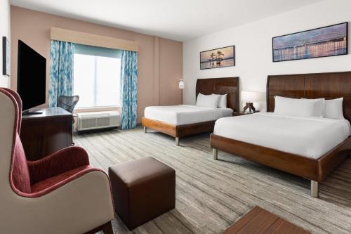 a hotel room with two beds and a chair at Hilton Garden Inn Memphis/Wolfchase Galleria in Memphis