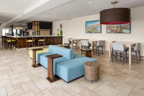 a living room with a blue couch and tables and chairs at Hilton Garden Inn Memphis/Wolfchase Galleria in Memphis