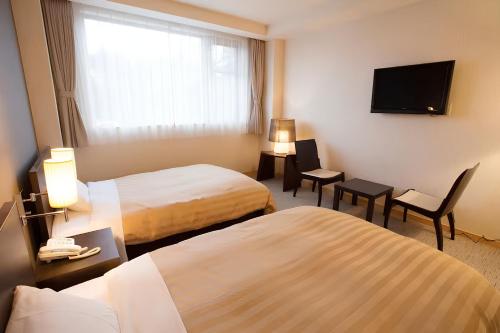 a hotel room with two beds and a flat screen tv at The Gran Resort Princess Fujikawaguchiko in Fujikawaguchiko