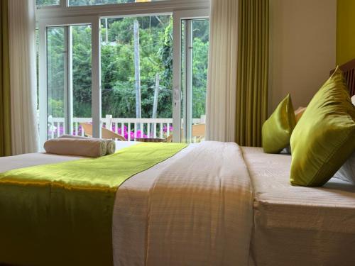 a bedroom with two beds and a large window at The Green Lodge Kandy in Kandy