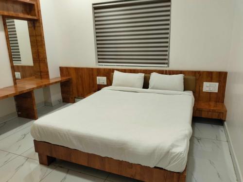 a bedroom with a bed with white sheets and a window at Hotel O New anugraha deluxe in Kulurkudrū