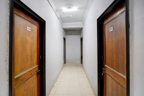 a hallway with two wooden doors and a tile floor at Hotel O Radha Residency in Badarpur
