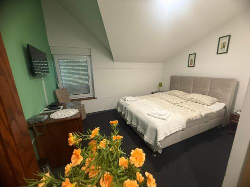 a bedroom with a bed and a desk and flowers at Hotel Višnjica in Španat