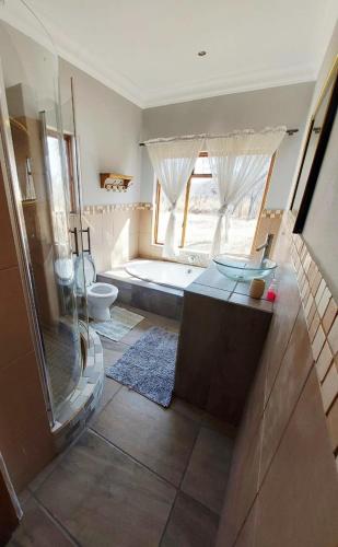 a bathroom with a shower and a tub and a toilet at Oryx Lodge in Brits