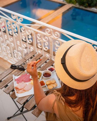 a woman in a hat sitting on a bench eating food at Fiftyfour West Boutique Living in Għarb