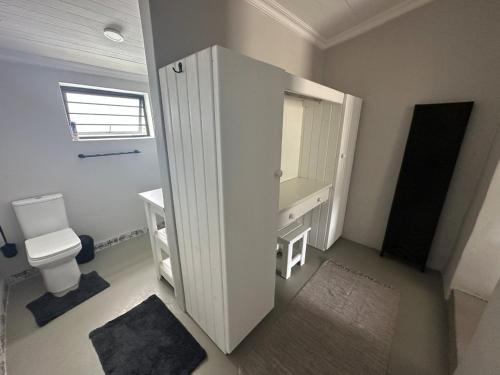 a white bathroom with a toilet and a sink at The Sheperd's Cottage in Joubertina