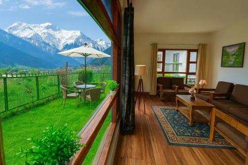 a living room with a balcony with a view of the mountains at Himalayan Crescent 2 Bedroom Luxury independent Villas Manali in Manāli