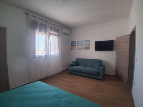 Una sala de estar con un sofá azul y un televisor. en Posidonia, en Lizzano