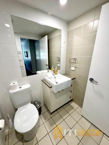 a bathroom with a toilet and a sink and a mirror at Comfortable & Spacious -2bd 2bth - Braddon in Canberra