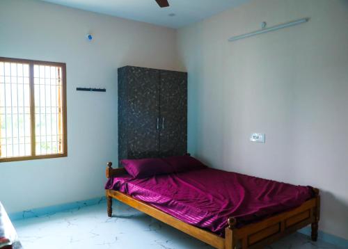 een slaapkamer met een bed met paarse lakens bij Nandhi home stay in Tiruvannamalai