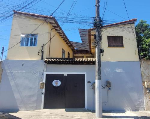 a house with a garage with a black door at Hospedagem dona Alaide in Paraty