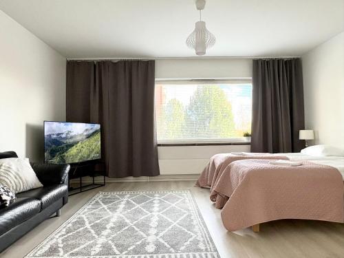 a bedroom with a bed and a couch and a window at Aava's apt. FREE Parking in Pori