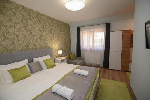 a bedroom with a large white bed with green pillows at Babér Vendégház Tokaj in Tokaj